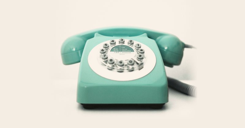 Turkos telefon med nummerskiva mot ljus bakgrund